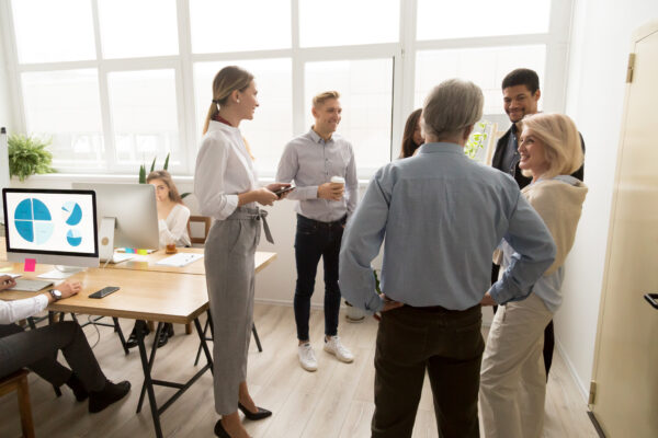 Team von Büroangestellten steht bei einem Daily Huddle zusammen.